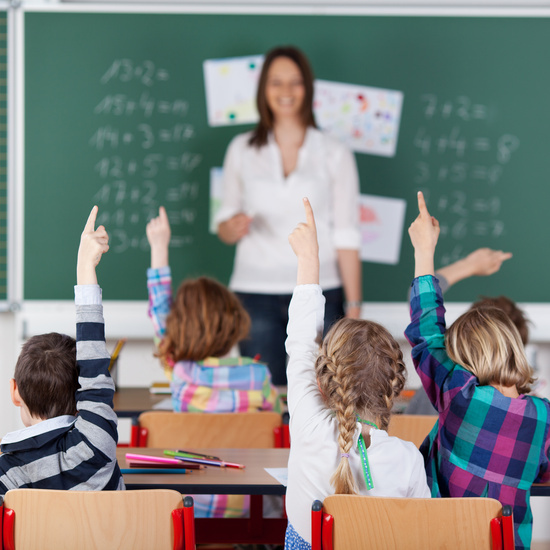 Children raising hands in a classroom